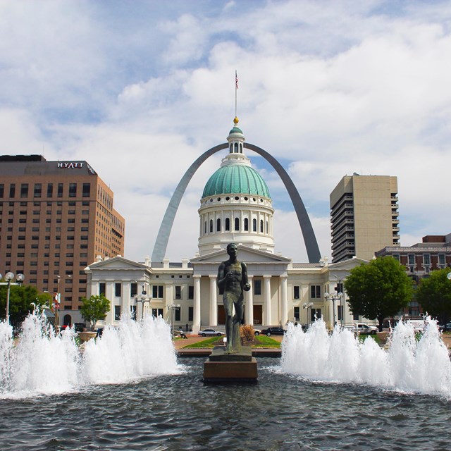 Courthouse building with Gateway Arch in background and fountain in front