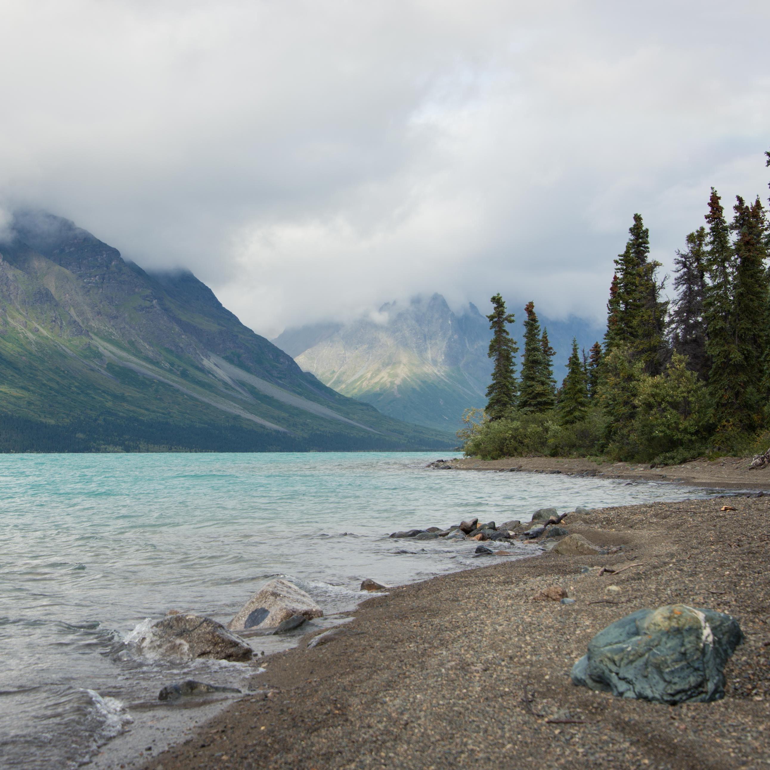 the turquoise waters of upper twin lake, with trees and mountains surrounding