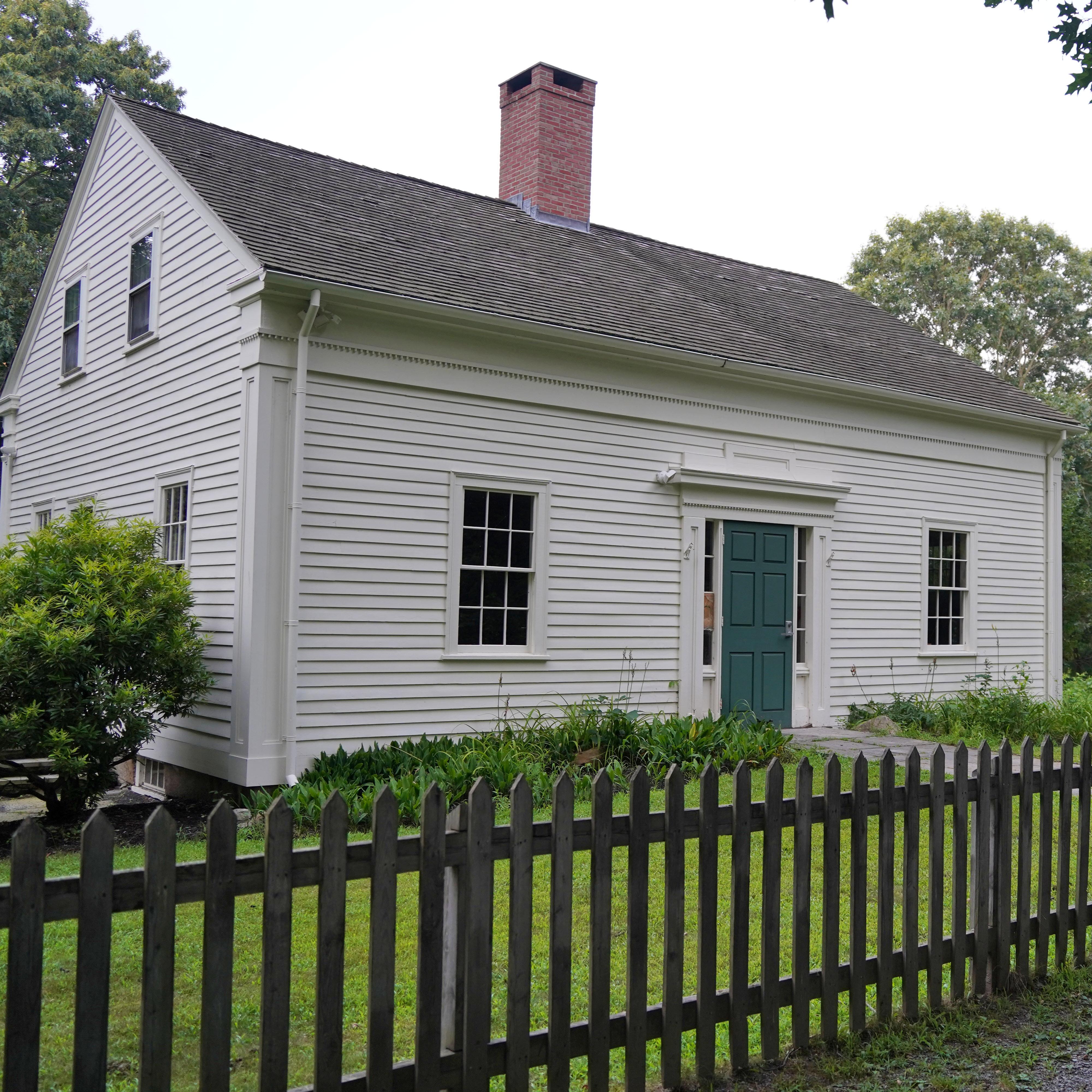 White, two-story house with brick center chimney and green door
