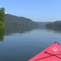 view of lake with trees on all sides from cockpit of a kayak