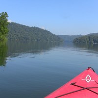 view of lake with trees on all sides from cockpit of a kayak 