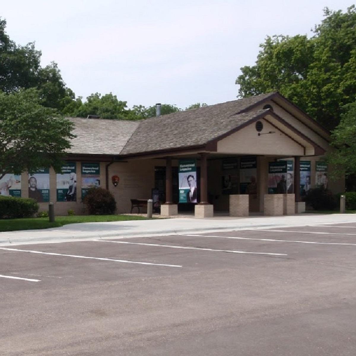 An l-shaped brick building with landscaped bushes and trees surrounding it.