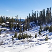 A landscape photo of a snow-covered hill with people playing and a building in the background.