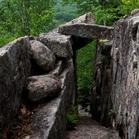 Rock bridge over a trail cut into granite