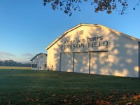 A white airplane hangar with the words "Army Air Corps, Pearson Field" painted on it in black.