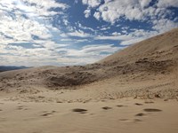 A cloudly blue sky above sand dunes