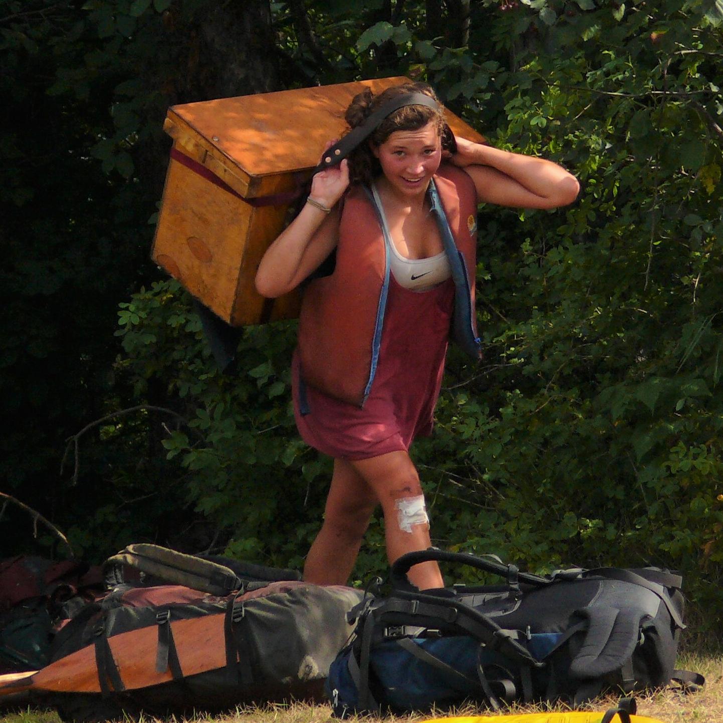 A person carrying a large box held in place with a head strap.