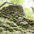 A rock formation that looks like columns stuck together in the woods on a sunny day.