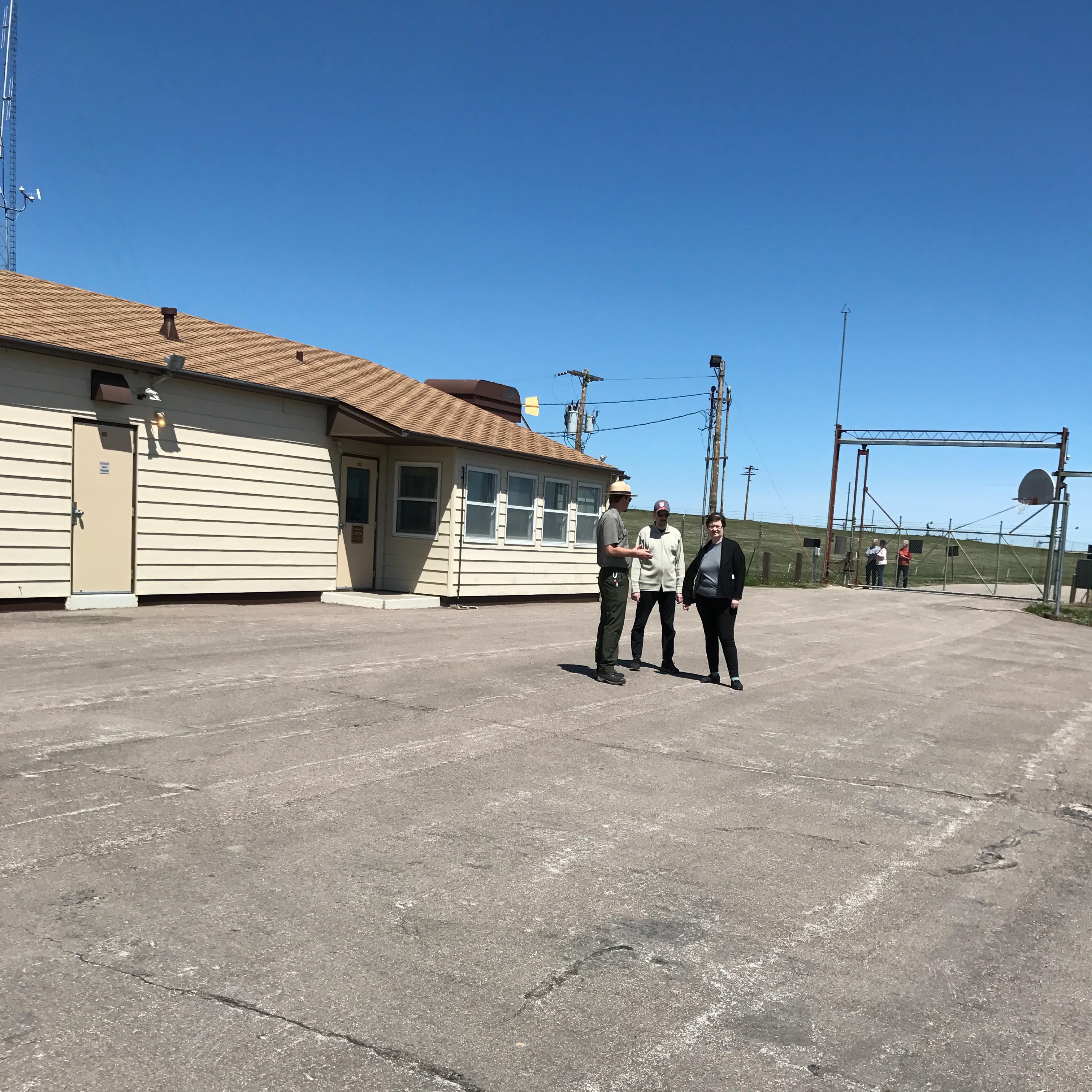 A park ranger with visitors inside a fenced compound
