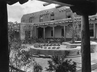 A historic black and white photo of a two story, adobe building.