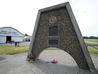 A triangular metal and stone monument with Pearson Air Museum in the background.