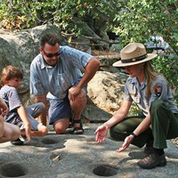 a ranger and a family examine mortar holes