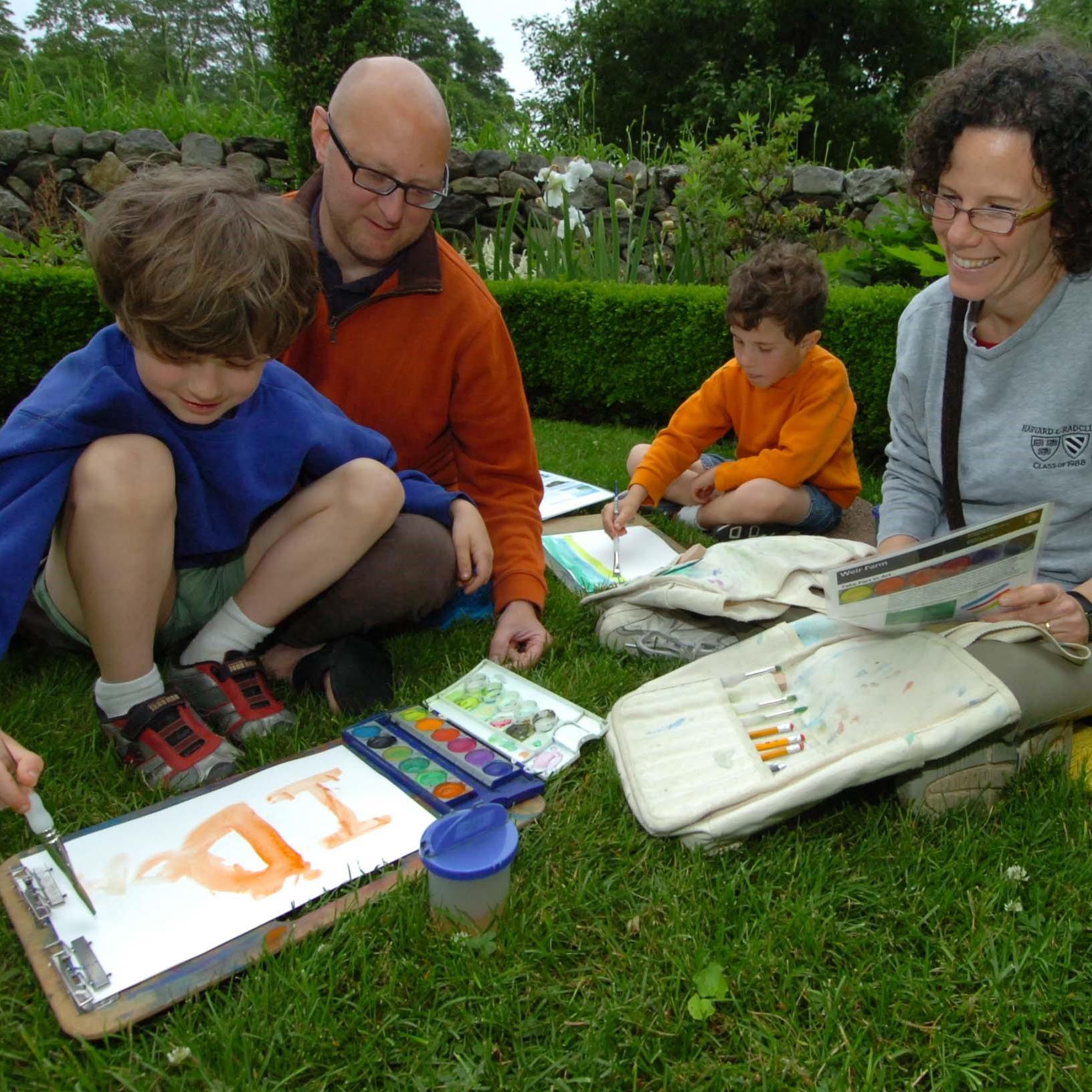 A family sitting in the grass painting.