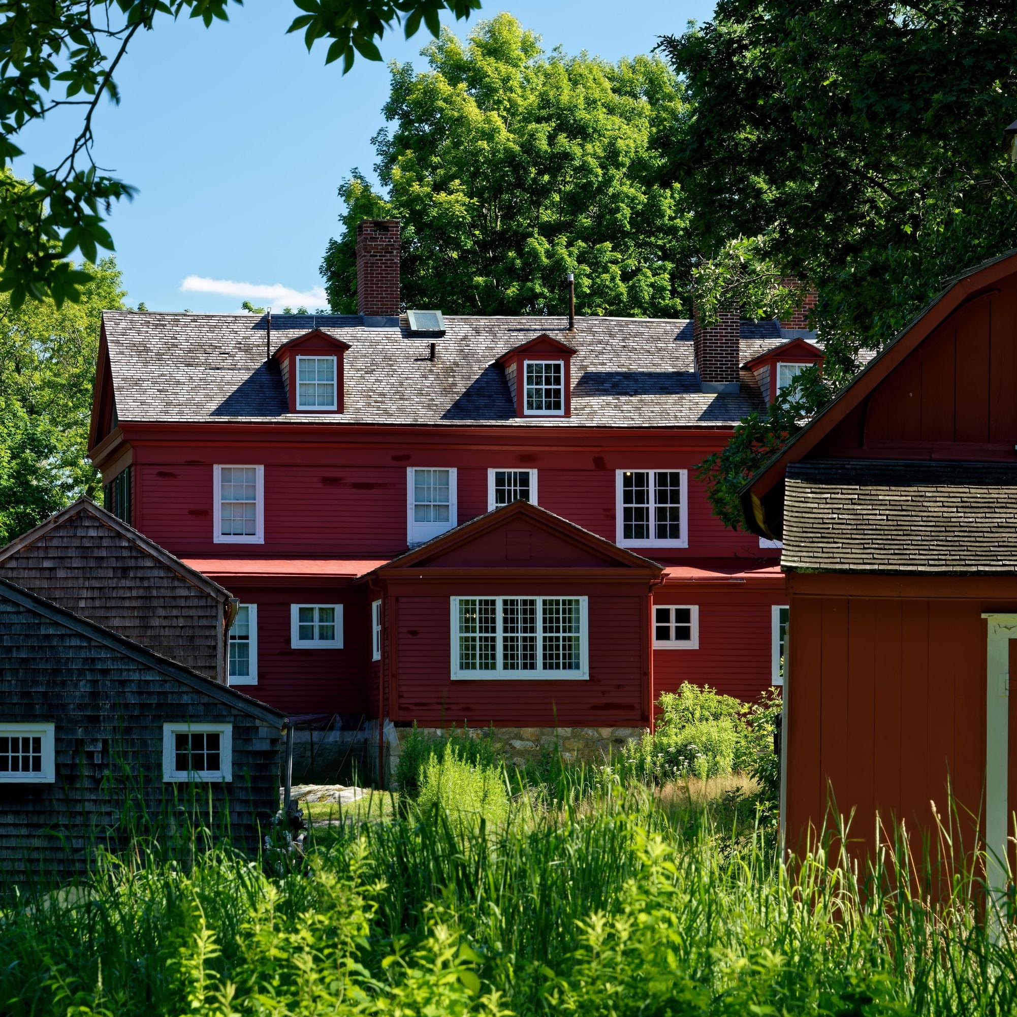 A back of a red house with two other buildings in front of it.