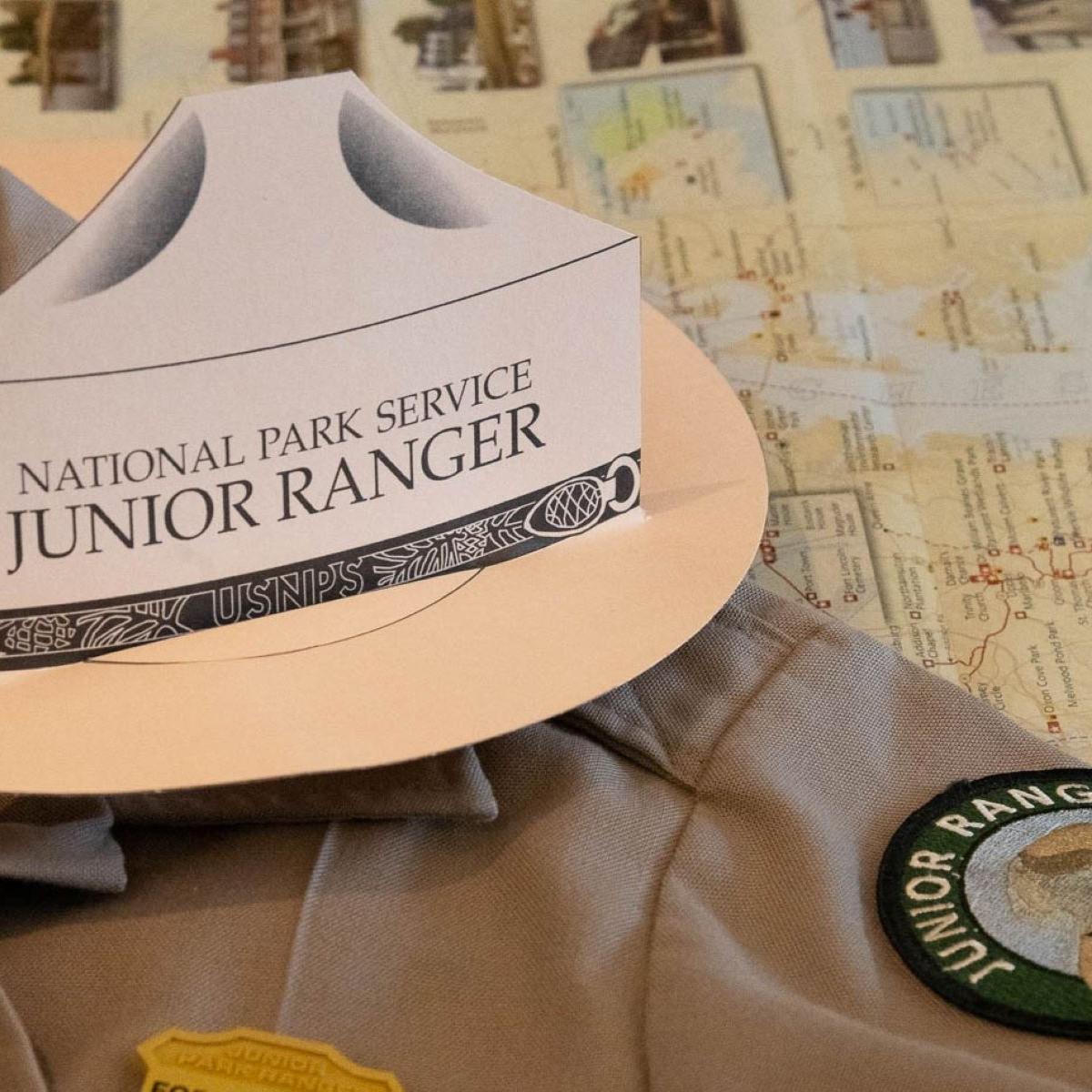 A shirt with a junior ranger badge, patch and hat on it.