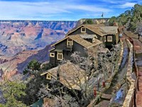 a rambling multi-story craftsman style wood frame building perched on the edge of a canyon cliff.