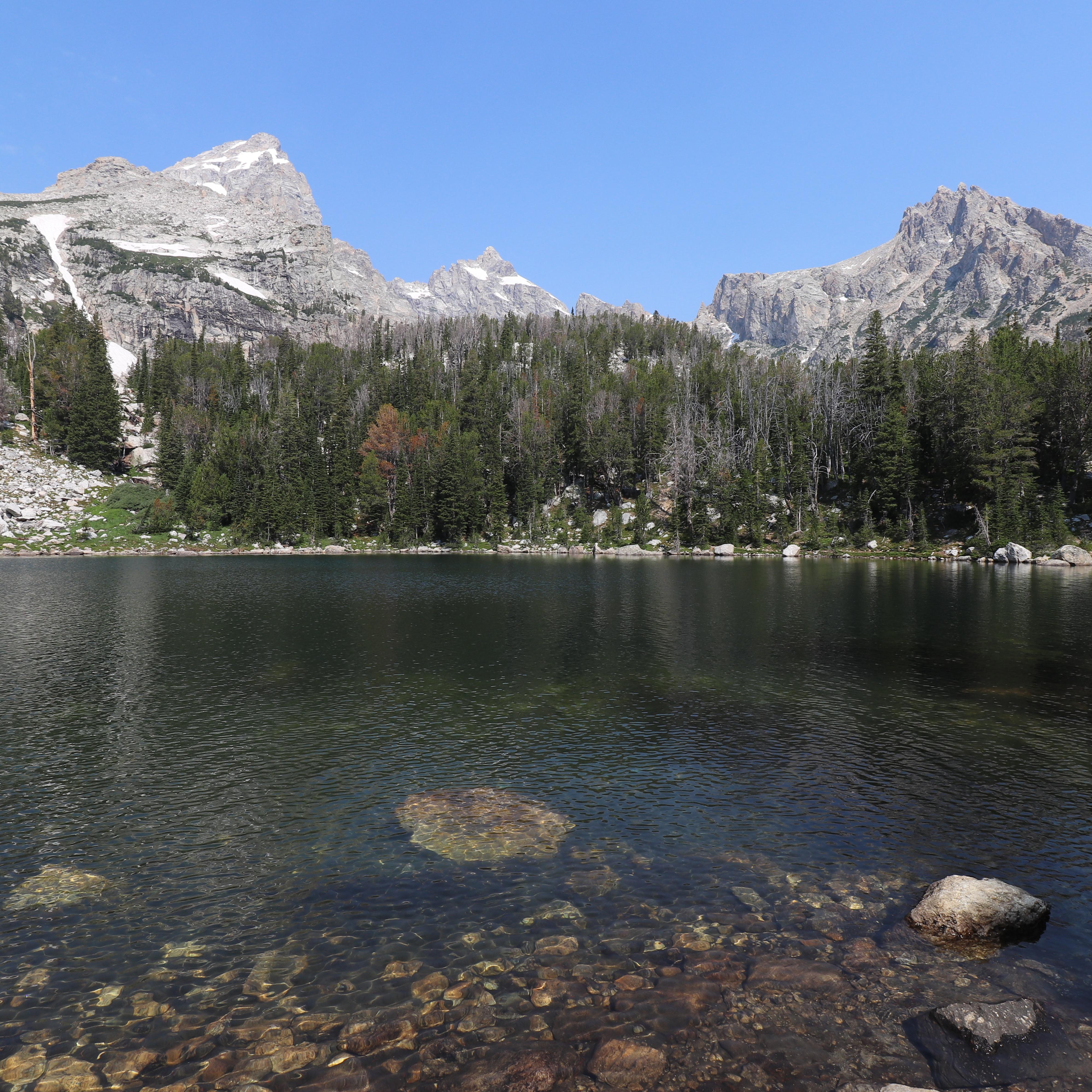An alpine lake sits beneath rocky mountain peaks.