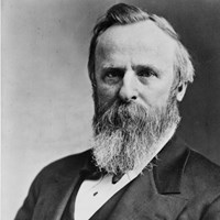 An 1800s half-length portrait photo depicts a seated man with a beard, facing left.
