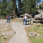 several visitors on paved path looking at wayside exhibit and surrounding scenery