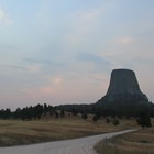 a pink sun rises into a cloudy morning sky with Devils Tower
