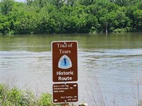 Trail of Tears mileage sign on edge of riverbank.