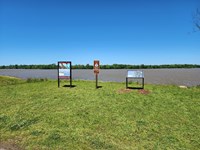 Trail of Tears exhibit, mileage sign, and exhibit about the Quapaw and Osage along riverfront with o