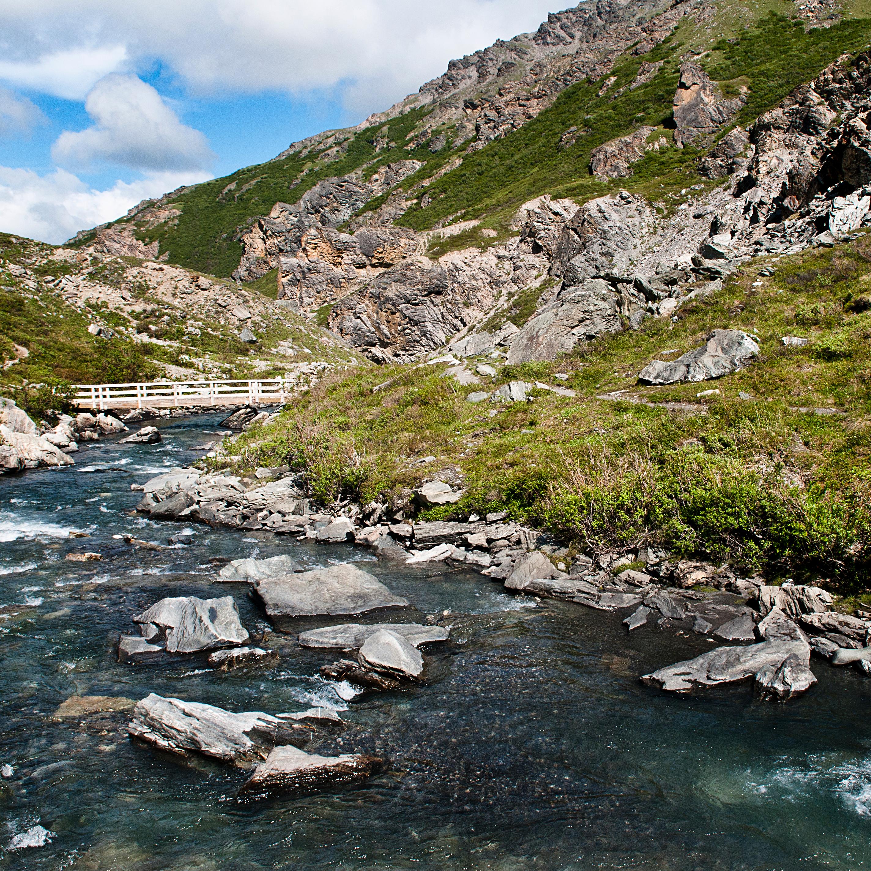 a shallow river flowing between mountains
