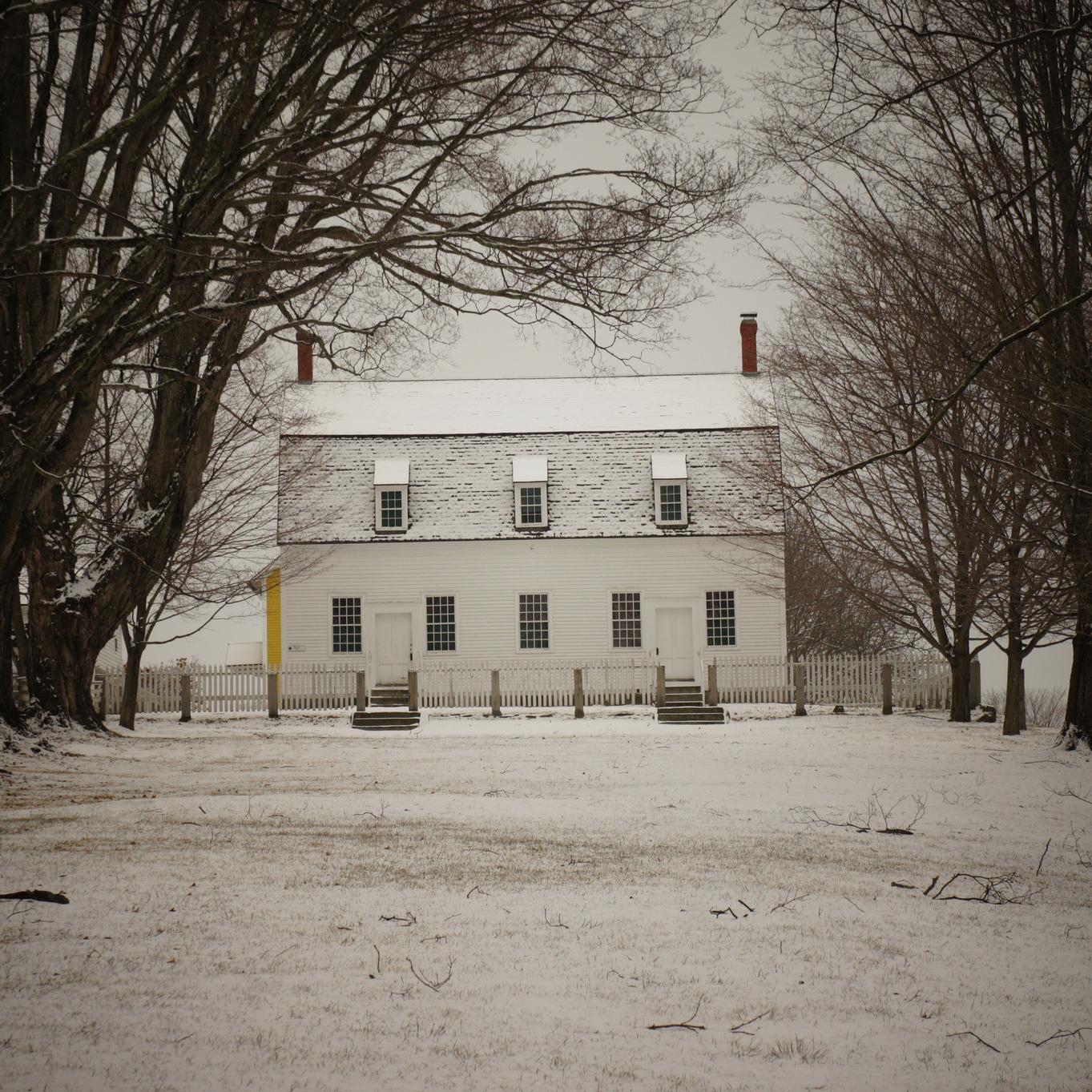 tree flanked common leading to a white clapboard building