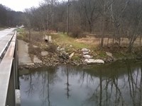 Next to a bridge is a thin, grassy trail that leads down to the Cuyahoga River