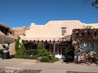 The front of an adobe building with a wooden porch.