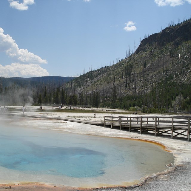 Brightly colored hot spring with boardwalk along edge