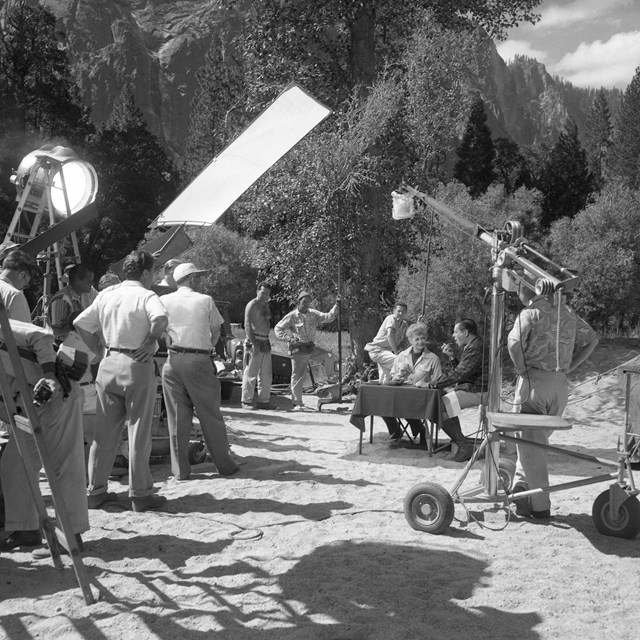 Black and white movie set during filming outside in a park