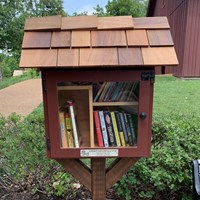 Collection of books inside red wooden box with cedar shingle roof.