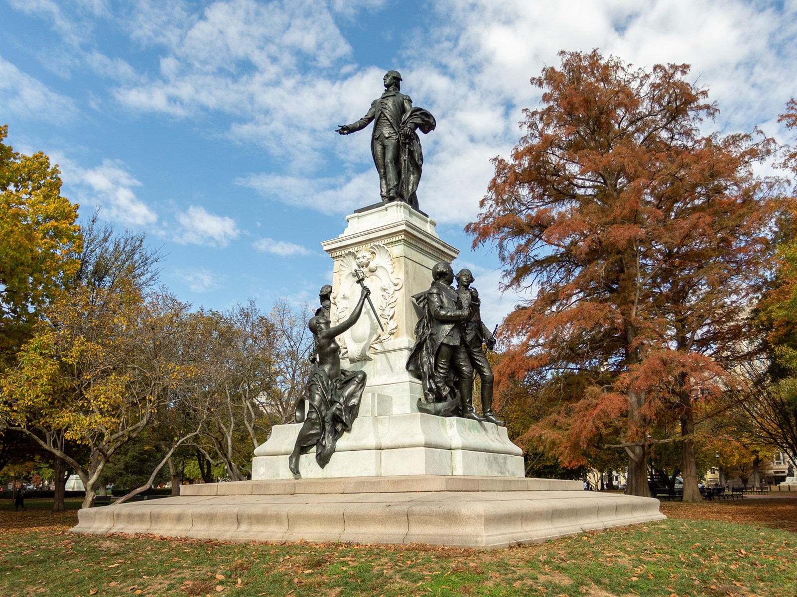 A bronze statue of Lafayette standing with hand outstretched. Other figures stand at the base.