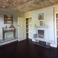 The parlor in the Poe House, a small room with illustrations of furniture but no real furniture.