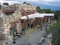 a roughhewn building made of rocks and logs with a porch with an overhanging roof above the entrance
