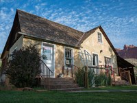 a small farmhouse with two sets of steps each leading up to a door