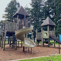A large play structure in a bark chip playground.