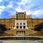 The front facade at Little Rock Central High School framed by blue skies and puffy clouds.