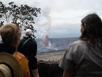 Visitors look into an erupting crater.