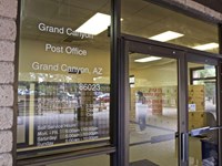 Looking through large glass windows and doors into the lobby and boxes in a post office