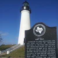 White lighthouse with State of Texas historical marker in the foreground.