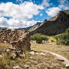 A trail continues past a rock wall marking the ruin of a stage station