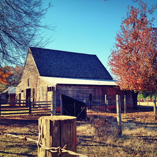 A side view of the wooden barn surrounded by a wooden fence at the Boyhood Farm.