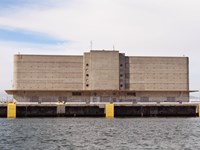 Multiple story historic building with curved sides. Dock and water.