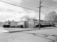 Historic photos of a one story building used as a school. Sits back from the street.
