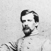 An 1800s full portrait photograph shows a young bearded man in an army uniform.