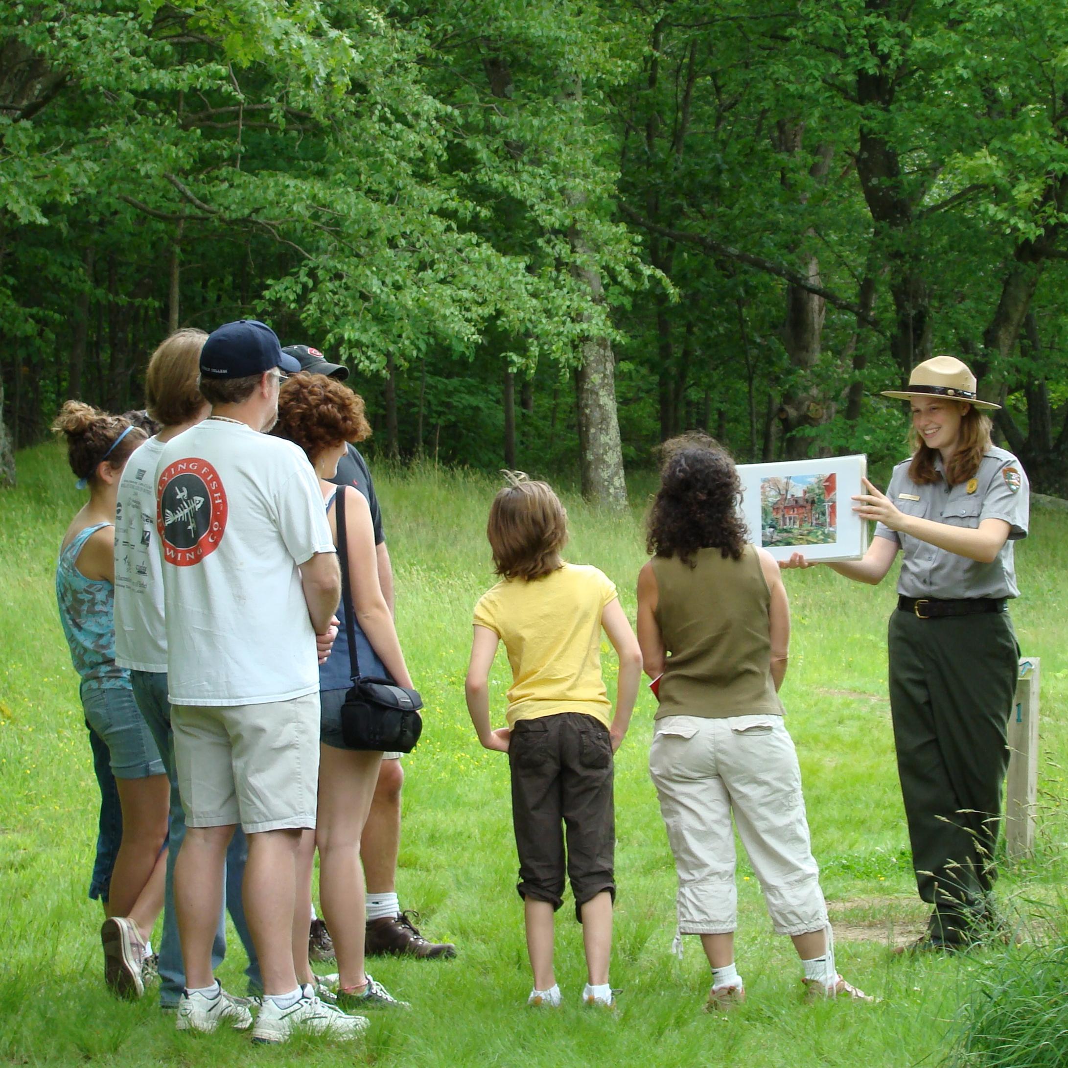 A ranger holding up an image with a group of visitors looking on.