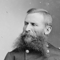 An 1870s half-portrait photo shows a fork-bearded man seated in double-breasted army uniform.