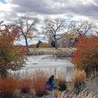 A girl runs on a path near a pond, surrounded by fall colors.